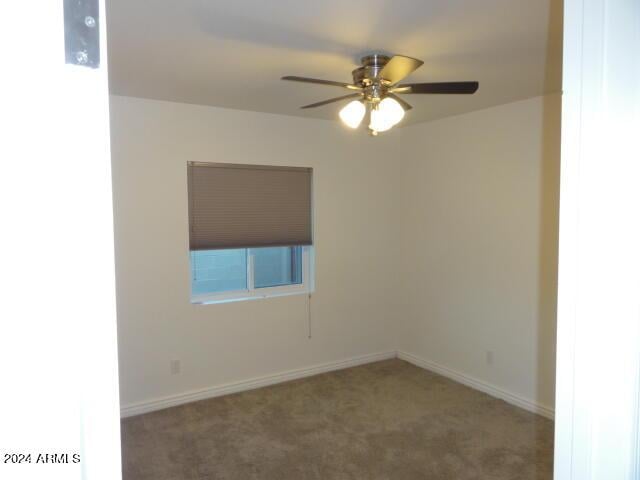 carpeted empty room with ceiling fan and baseboards