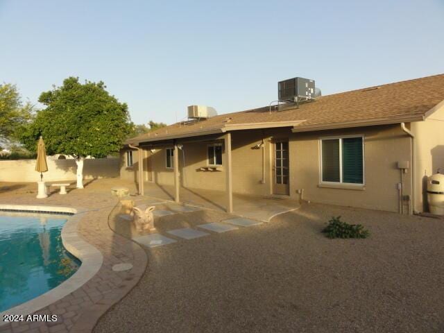 back of property with an outdoor pool, stucco siding, a patio, and central AC