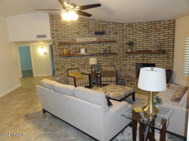 living room featuring vaulted ceiling, a ceiling fan, visible vents, and baseboards