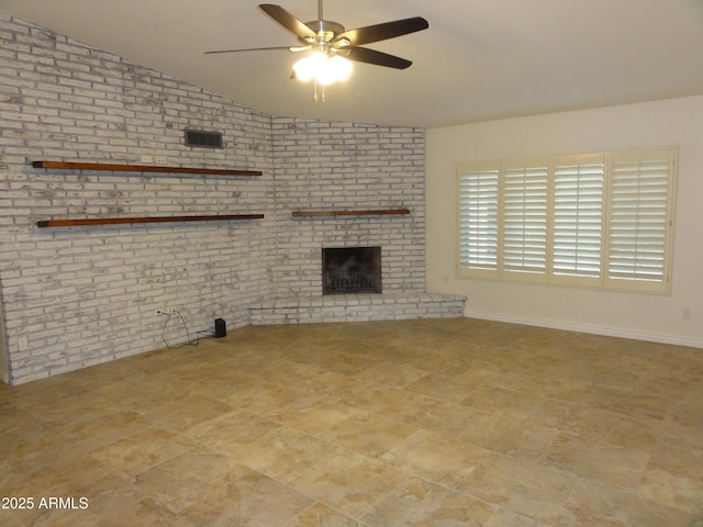 unfurnished living room with a ceiling fan, lofted ceiling, a fireplace, and brick wall