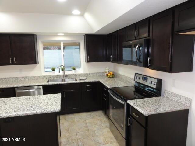 kitchen with a raised ceiling, recessed lighting, appliances with stainless steel finishes, and a sink