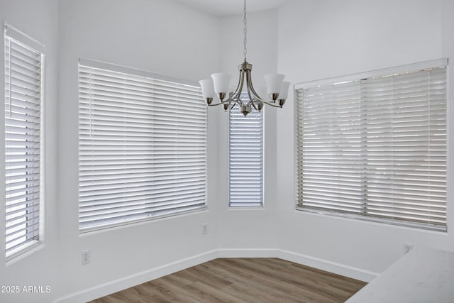 6368 W Firebird Dr, Glendale, AZ 85308 - unfurnished dining area featuring a chandelier, wood finished floors, baseboards, and plenty of natural light