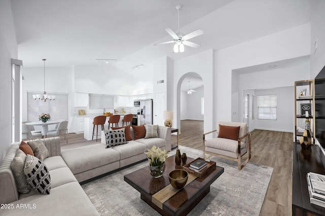 6368 W Firebird Dr, Glendale, AZ 85308 - living room featuring ceiling fan, light wood-style floors, high vaulted ceiling, arched walkways, and a chandelier