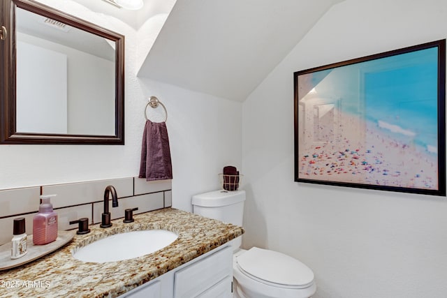 bathroom with vanity, visible vents, toilet, and lofted ceiling