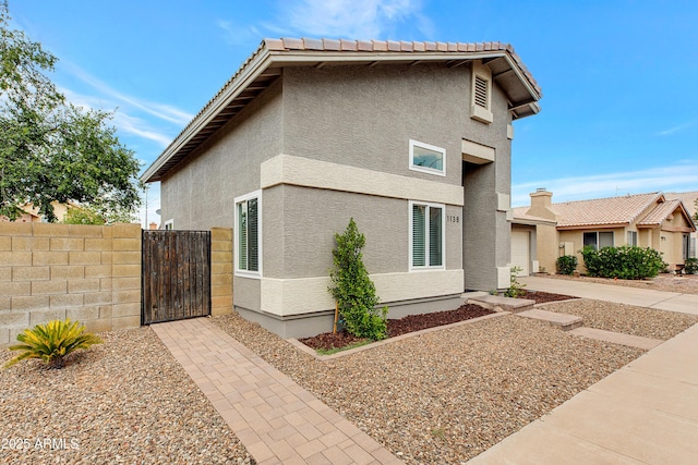 view of home's exterior with fence, a gate, and stucco siding