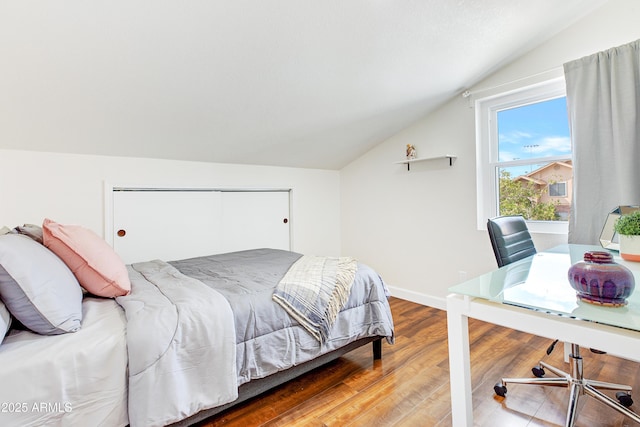 bedroom featuring baseboards, wood finished floors, and lofted ceiling