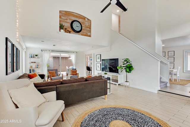 living room with stairs, a high ceiling, a wealth of natural light, and ceiling fan