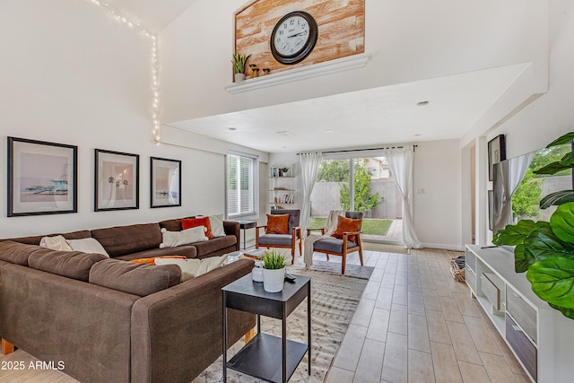 living room with light wood-style floors, baseboards, and a towering ceiling