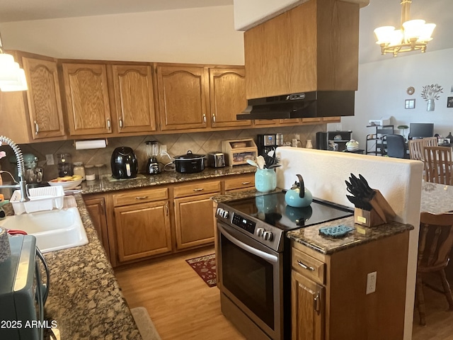 kitchen featuring electric stove, sink, an inviting chandelier, decorative backsplash, and light wood-type flooring