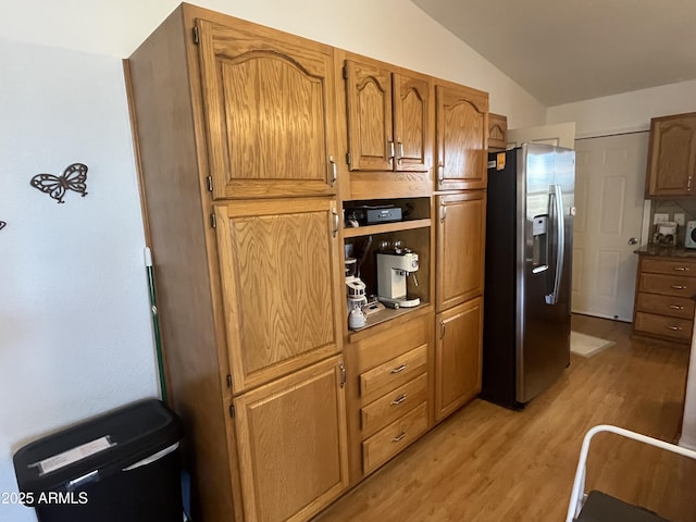 kitchen featuring vaulted ceiling, light wood-type flooring, and stainless steel fridge with ice dispenser