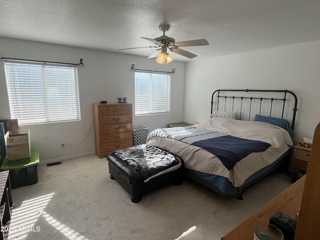 bedroom featuring ceiling fan, light colored carpet, and a textured ceiling