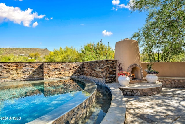 view of swimming pool featuring an outdoor stone fireplace and a patio area