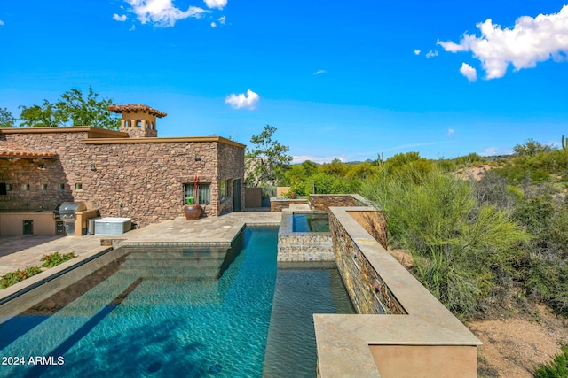 view of swimming pool featuring an in ground hot tub, area for grilling, and a patio area