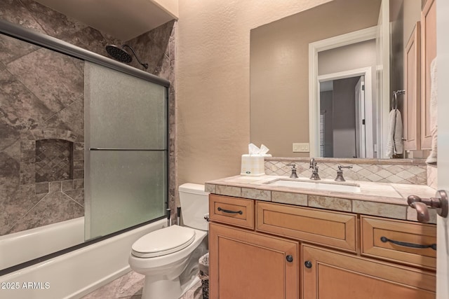 full bathroom featuring vanity, toilet, combined bath / shower with glass door, and tasteful backsplash