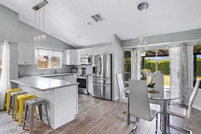 20822 N 34th Dr, Phoenix, AZ 85027 - kitchen featuring appliances with stainless steel finishes, a chandelier, lofted ceiling, a peninsula, and tasteful backsplash