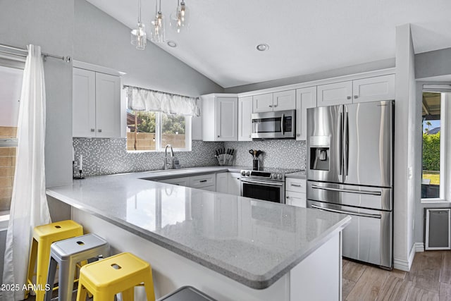 20822 N 34th Dr, Phoenix, AZ 85027 - kitchen with appliances with stainless steel finishes, lofted ceiling, a peninsula, white cabinetry, and light wood finished floors