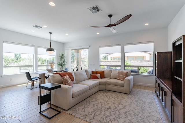 living room with a wealth of natural light, ceiling fan, and light wood-type flooring