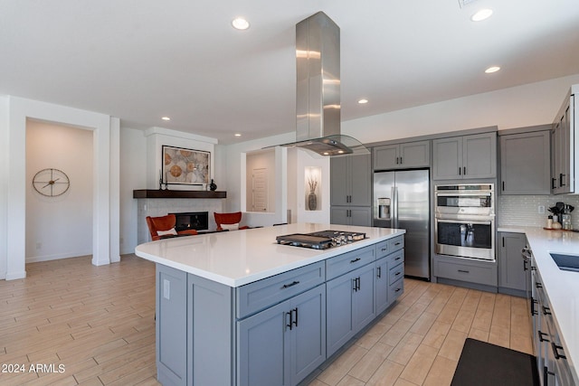 kitchen with backsplash, stainless steel appliances, a kitchen island, and island range hood