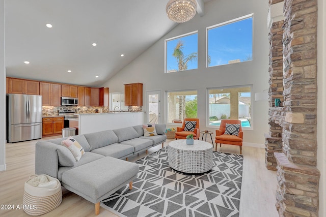 living room with light wood-type flooring, high vaulted ceiling, sink, and a notable chandelier