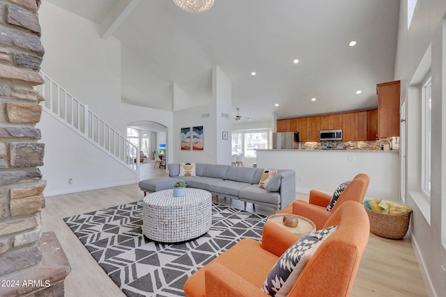 living room with light wood-type flooring, high vaulted ceiling, and ceiling fan