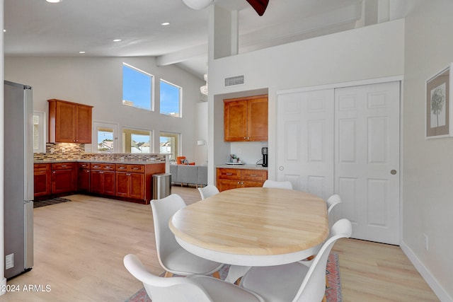 dining area with high vaulted ceiling, beamed ceiling, and light hardwood / wood-style flooring