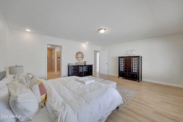 bedroom with light wood-type flooring and ensuite bath