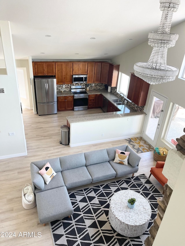 living room featuring light wood-type flooring, plenty of natural light, a chandelier, and sink