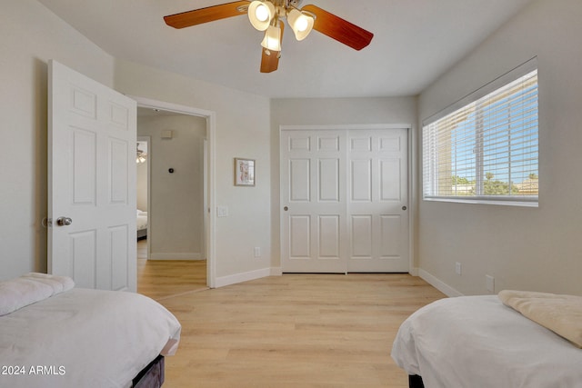 bedroom featuring light wood-type flooring, ceiling fan, and a closet