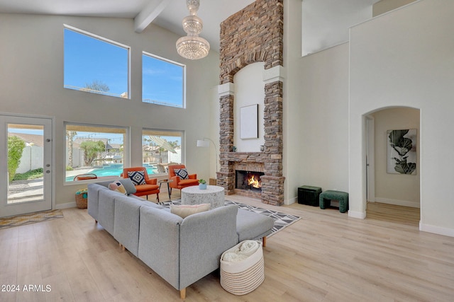 living room featuring a fireplace, an inviting chandelier, light wood-type flooring, beamed ceiling, and high vaulted ceiling