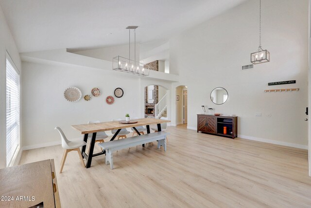 dining room featuring high vaulted ceiling and light hardwood / wood-style floors