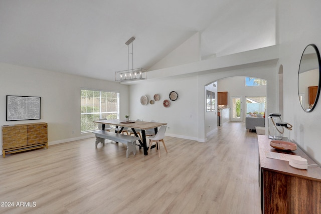 dining space featuring light wood-type flooring and high vaulted ceiling