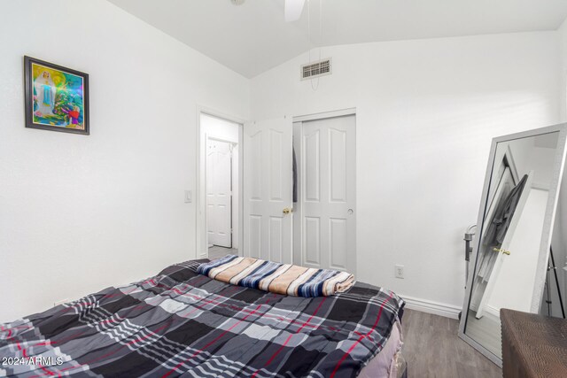 bedroom with ceiling fan, a closet, wood-type flooring, and vaulted ceiling