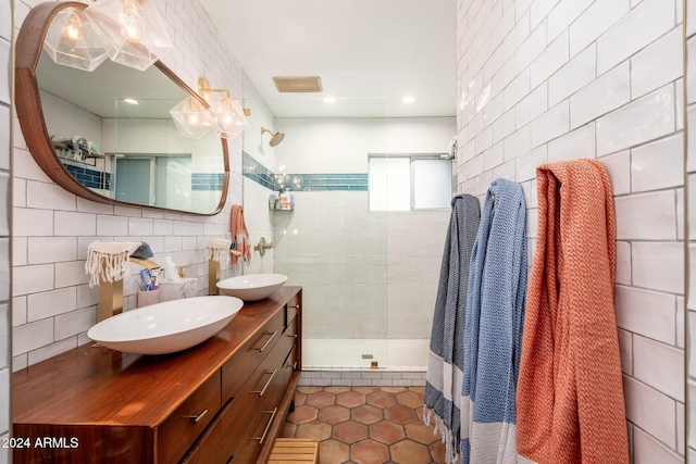 bathroom with tile patterned flooring, a tile shower, vanity, and tile walls