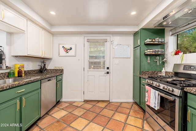 kitchen with dark stone counters, exhaust hood, green cabinetry, white cabinetry, and stainless steel appliances