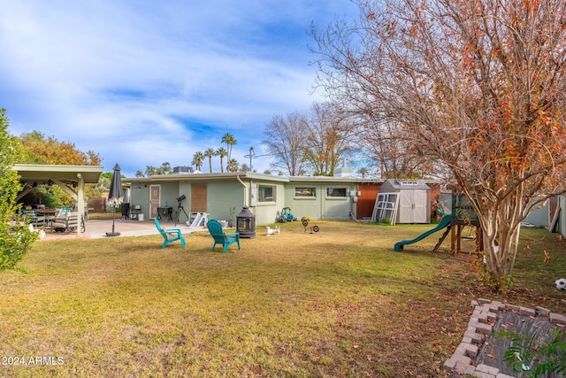 back of property featuring a lawn, a playground, a patio, and a shed