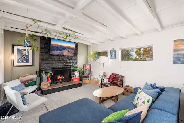 living room featuring beam ceiling, a stone fireplace, and concrete flooring