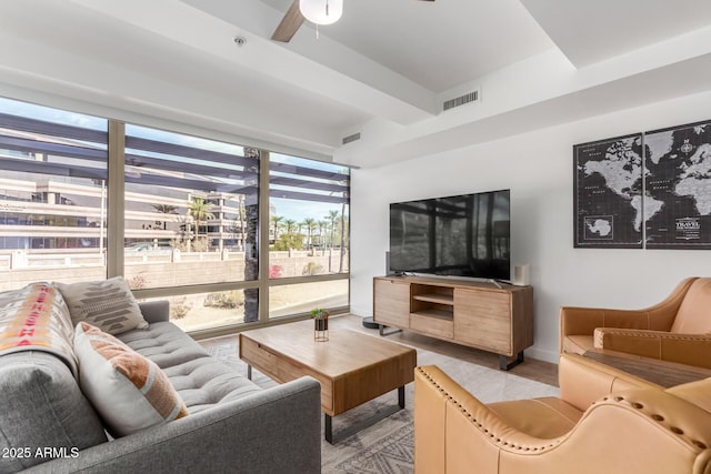 living room with light wood-type flooring, baseboards, visible vents, and a wall of windows