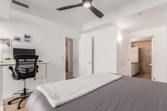 bedroom with ensuite bathroom, wood finished floors, visible vents, and a ceiling fan