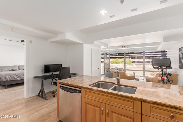 kitchen featuring a sink, light wood-style floors, open floor plan, light stone countertops, and dishwasher