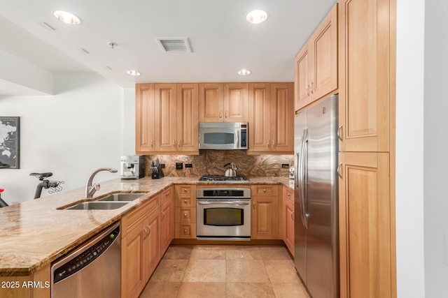 kitchen featuring visible vents, appliances with stainless steel finishes, light stone counters, a peninsula, and a sink