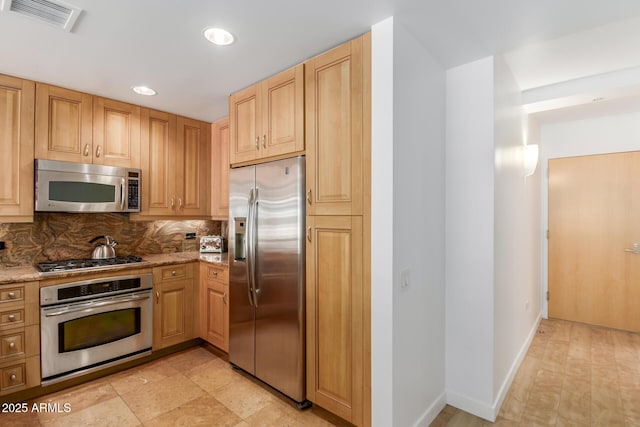 kitchen featuring light stone counters, appliances with stainless steel finishes, visible vents, and tasteful backsplash