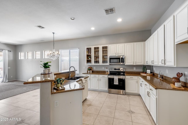 6742 W El Cortez Pl, Peoria, AZ 85383 - kitchen with stainless steel appliances, a sink, glass insert cabinets, light tile patterned flooring, and white cabinetry