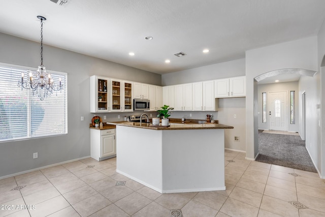 6742 W El Cortez Pl, Peoria, AZ 85383 - kitchen featuring stainless steel microwave, dark countertops, glass insert cabinets, light tile patterned floors, and recessed lighting