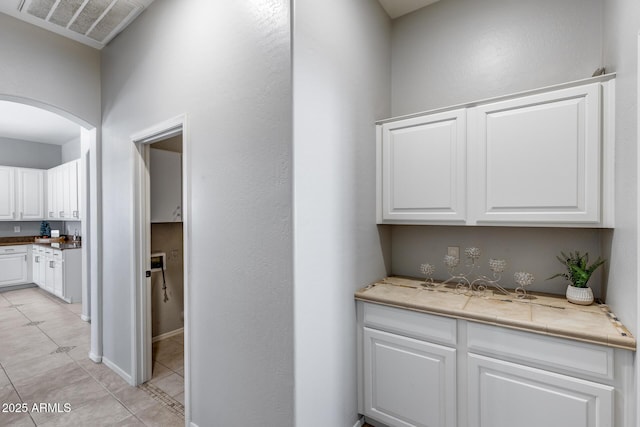 6742 W El Cortez Pl, Peoria, AZ 85383 - bar area featuring arched walkways, light tile patterned floors, and baseboards