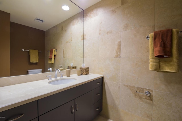 bathroom with tile walls, vanity, and toilet