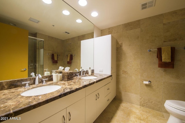 bathroom featuring walk in shower, vanity, tile walls, and toilet