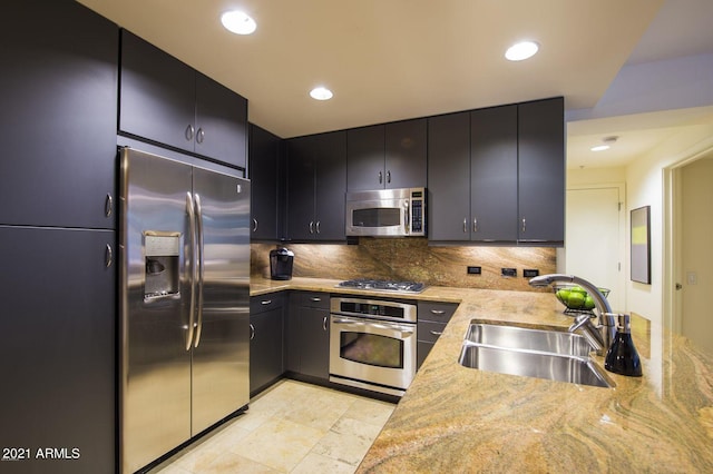 kitchen with backsplash, sink, stainless steel appliances, and light stone counters