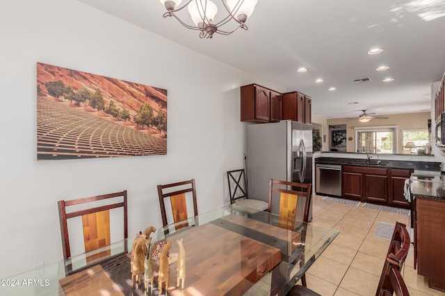 dining area with sink, light tile patterned floors, and ceiling fan with notable chandelier