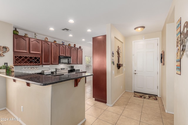 kitchen with kitchen peninsula, dark stone counters, a breakfast bar, light tile patterned floors, and stainless steel electric range