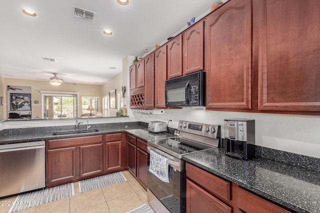 kitchen with dark stone counters, sink, ceiling fan, light tile patterned floors, and appliances with stainless steel finishes